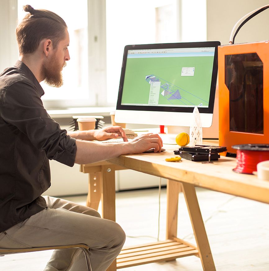 Étudiant en modélisation 3D sur ordinateur avec imprimante 3D, formation Design Prototypage Strate